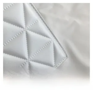 Detail der weißen gesteppten Kunstleder-Textur mit feinen Nähten an der kleinen Tasche