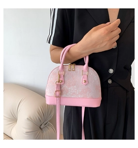 Detail of pink shell bag featuring white floral jacquard texture and golden zippers