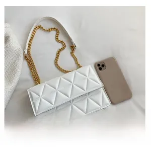 Draufsicht auf weiße gesteppte Umhängetasche mit goldener Kette neben einem Smartphone