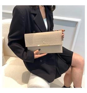 Détail d'une pochette enveloppe beige embossée crocodile avec boucle dorée élégante