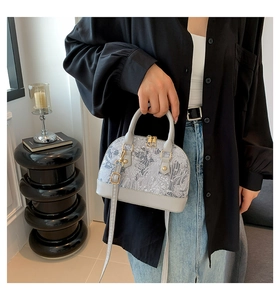 Detail of grey shell handbag with floral jacquard fabric and smooth leather accents