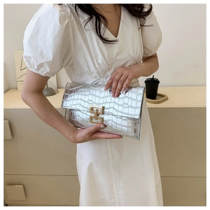 Detail of silver crocodile pattern envelope clutch with gold metal clasp closure