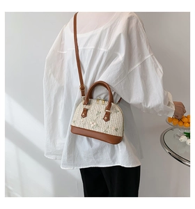 Detailed embroidery on vintage shell-shaped straw bag with elegant leather handles
