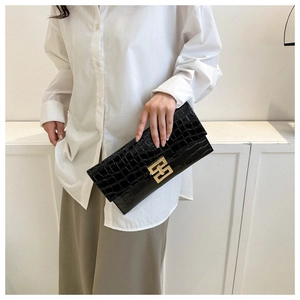 Macro shot of black crocodile texture clutch bag with elegant golden square metal buckle