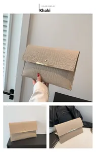 Détail d'une pochette enveloppe kaki avec texture crocodile et fermoir en métal doré