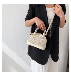 Mini shell-shaped straw bag with floral embroidery and dual handles on a black blazer