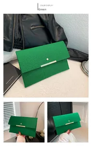 Détail d'une pochette enveloppe verte à motif crocodile avec garniture métallique dorée