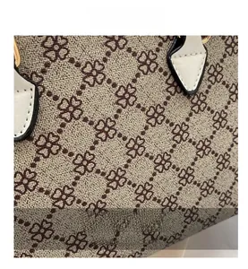 Detail of vintage beige textured fabric with brown clover lattice pattern and leather trim