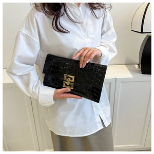 Detail of black crocodile texture envelope clutch with gold metal buckle closure