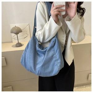 Détail du sac en denim bleu montrant la texture plissée et la large bandoulière réglable