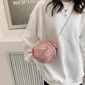 Sac bandoulière rose en forme de basket avec chaîne dorée porté par un mannequin en sweat blanc