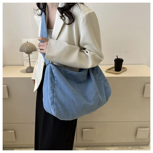 Sac hobo en denim bleu clair porté par un mannequin dans un intérieur moderne