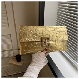 Close-up of golden faux leather clutch bag with crocodile texture and gold metal clasp