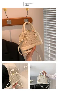 Detail of cream woven shell handbag with floral embroidery and golden hardware
