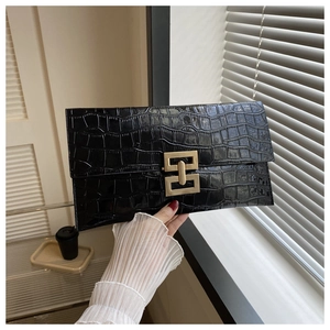 Detail of black faux crocodile leather envelope clutch with a gold interlocking metal clasp