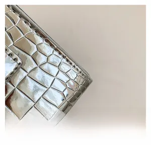 Detailed close-up of silver crocodile embossed leather handbag with reinforced stitching