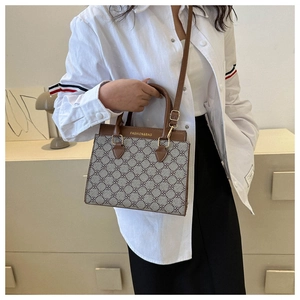 Detail view of the floral canvas texture and brown leather strap on a stylish handbag
