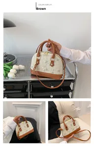 Detail of straw shell bag with floral embroidery and brown leather trim handles
