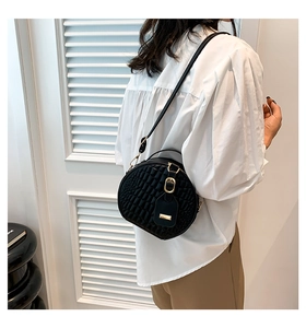Fashionable black round crossbody bag with crocodile pattern texture on white shirt