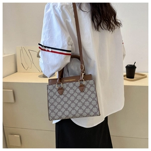 Detailed side view of a gray crossbody bag with floral pattern and brown leather straps