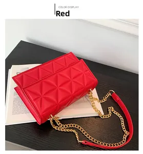 Detail der roten gesteppten Umhängetasche mit elegantem Goldkettenriemen auf dem Tisch