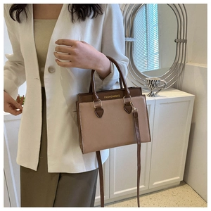 Detail of a brown and beige patchwork tote bag with gold hardware and shoulder strap