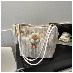 Detail der cremefarbenen Stroh-Tote-Bag mit floralen Akzenten und elegantem Spitzenband