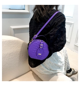 Detail of purple crocodile-patterned round crossbody bag with adjustable strap and gold zipper