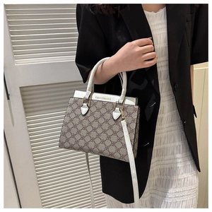 Detail of a brown clover pattern crossbody bag with white leather handles and gold metal accents