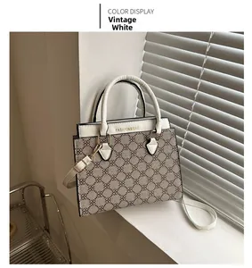 Detail of monogram white crossbody bag with gold hardware and top handles