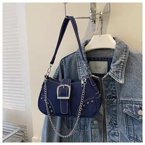 Detail view of navy canvas shoulder bag with silver buckle, rivets and chain strap