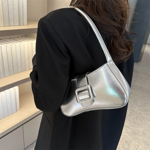 Silver metallic Y2K shoulder bag with large square buckle on a model in a library