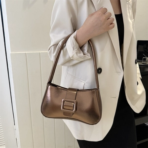 Metallic bronze underarm bag with decorative buckle shown in a stylish hand-carried pose