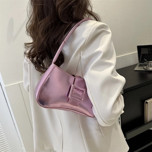 Pink metallic baguette bag with square buckle held by model in white blazer