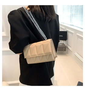 Close-up of beige quilted PU leather crossbody bag with silver chain strap on shoulder