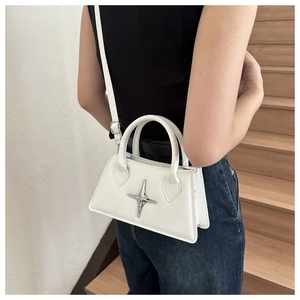 Detail of white leather crossbody bag with silver star ornament on wooden stairs