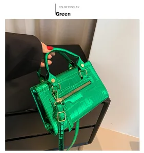 Close-up of metallic green crocodile pattern texture and golden zipper detail on handbag