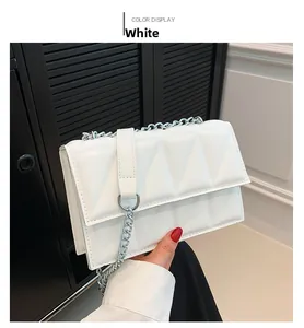 Detail of white rectangular shoulder bag with geometric quilted pattern and silver chain