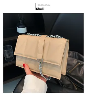 Detail of khaki quilted crossbody bag with silver chain straps and flap closure
