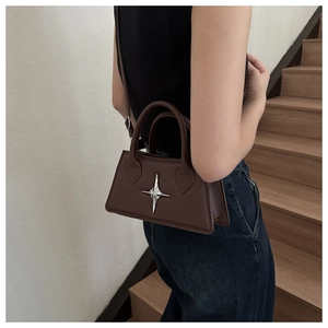 Detail of a dark brown leather mini bag with silver star emblem on staircase