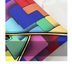 Macro view of geometric pattern and gold trim on cross-grain leather envelope bag