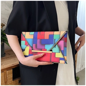 Detail of a geometric color-block envelope clutch bag with elegant gold metal trim