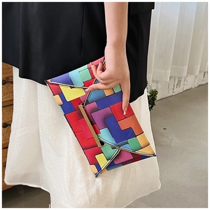 Detail of colorful geometric pattern clutch bag with gold metal edge trim on envelope flap