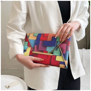 Detail view of a colorful geometric patchwork envelope bag with gold metal clasp