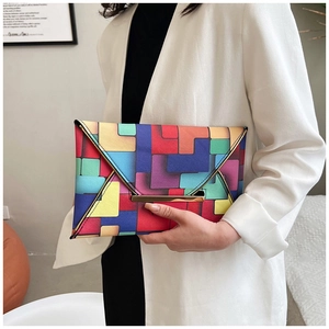 Macro detail of geometric color block clutch bag with gold metal trim and envelope flap