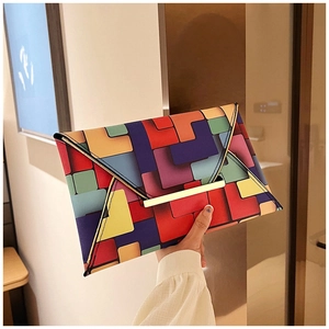 Detail showing the colorful geometric pattern and gold metal trim on the envelope clutch bag