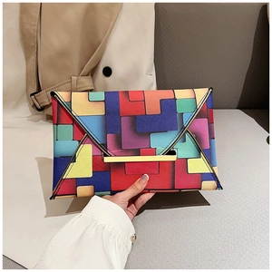 Detail of geometric patchwork envelope bag with golden metal bar lock and flap