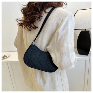Minimalist black quilted baguette shoulder bag styled with a light linen blazer