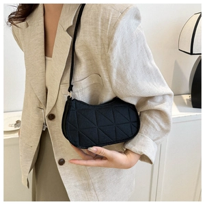 Close-up of black quilted half-moon shoulder bag featuring 3D geometric triangle texture