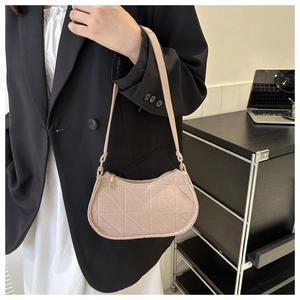 Detail of beige shoulder bag featuring geometric quilted pattern and gold zipper closure